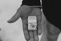 a black and white photo of a person holding a small box of cigarettes