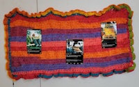 a colorful crocheted blanket hanging on a wall