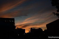 a sunset over a city with buildings in the background