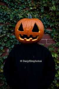 a man in a black hoodie with a pumpkin on his head